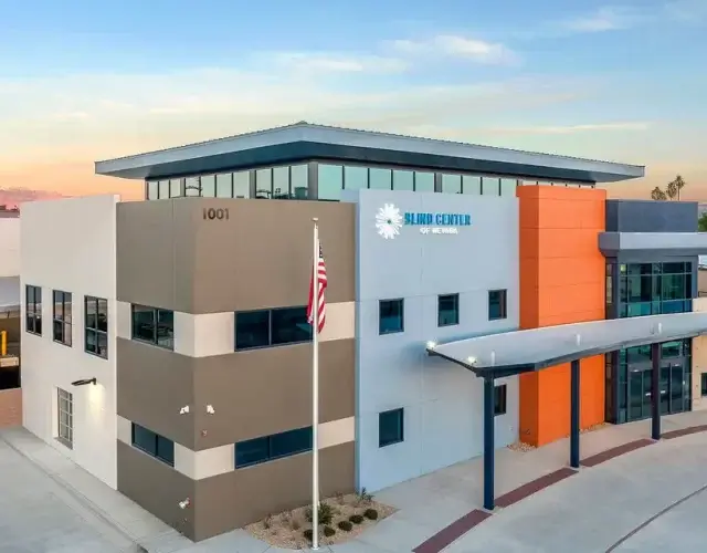 A large, block-colored building that is white, tan, orange and blue with the Blind Center of Nevada sign at the top.