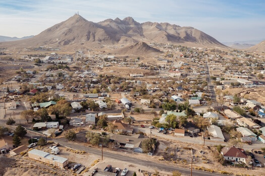 picture of a rural spread of the Nevada landscape with mountains in the background and homes in front of it.